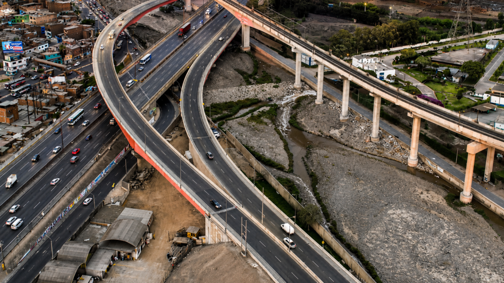 Vista aérea del viaducto de la Vía de Evitamiento y el proyecto Vía Parque Rímac (Línea Amarilla) cruzando sobre el cauce del río Rímac en Lima.